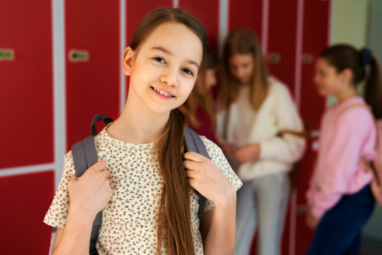 Uczennica z plecakiem przy szafkach na szkolnym korytarzu